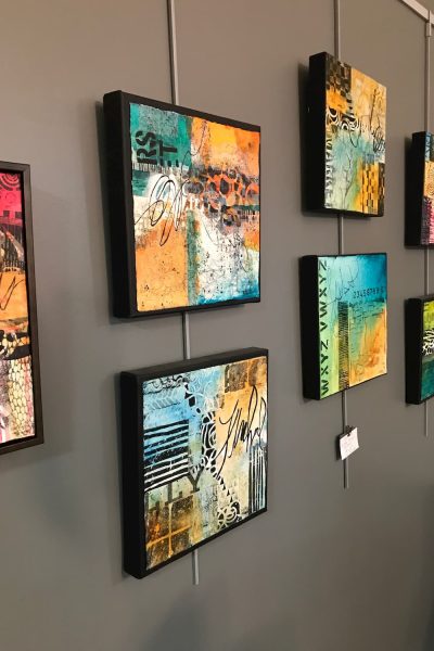 Mixed media paintings hanging in a studio during the 2019 Meander Art Crawl.